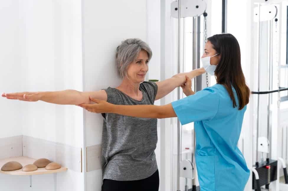 fisioterapeuta ayudando a paciente mayor ejercicios fisioterapia