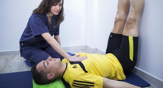 fisioterapeuta mujer ayudando con postura a paciente